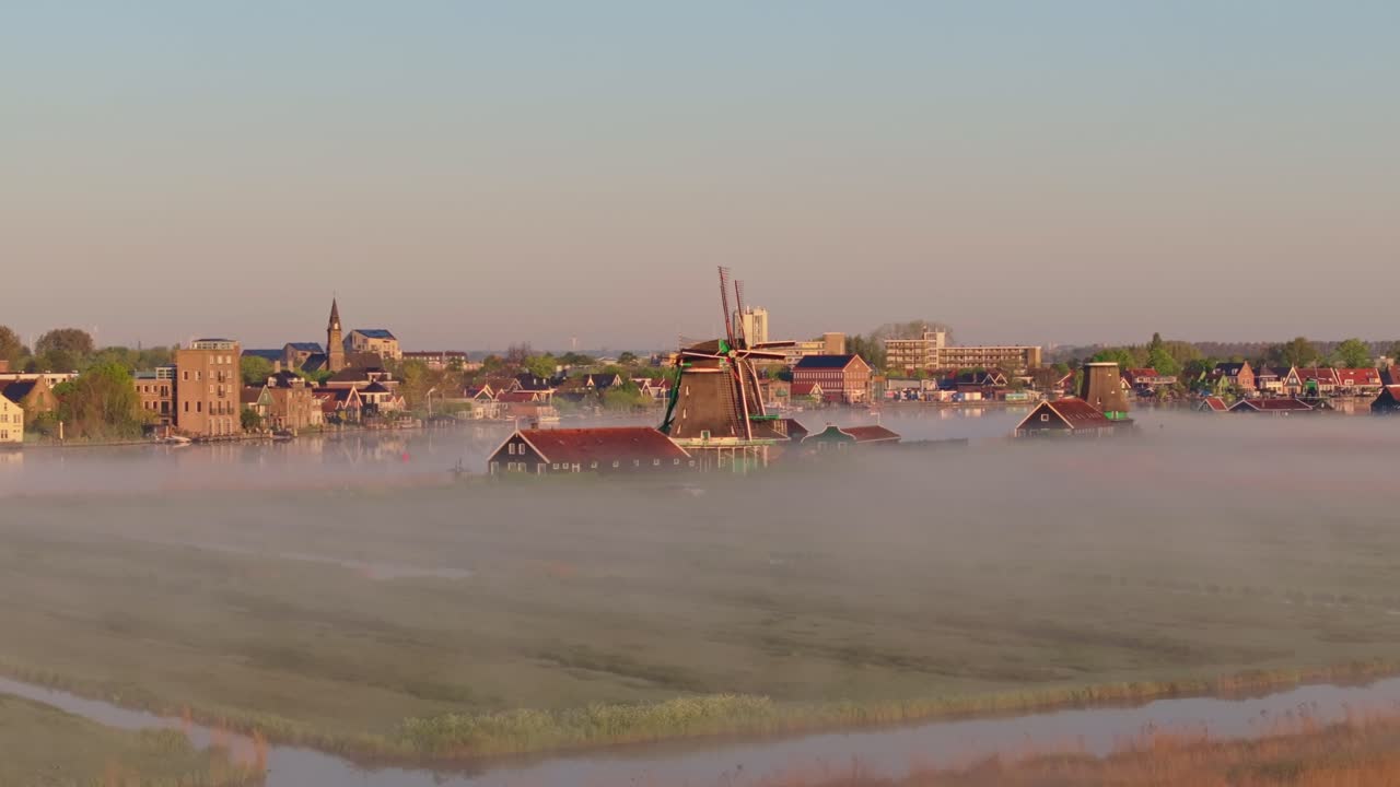 Vista aerea degli iconici mulini a vento di Zaanse Schans avvolti nella nebbia mattutina.