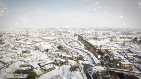 composición digital de las estructuras moleculares flotando contra la vista aérea del paisaje urbano cubierto de nieve