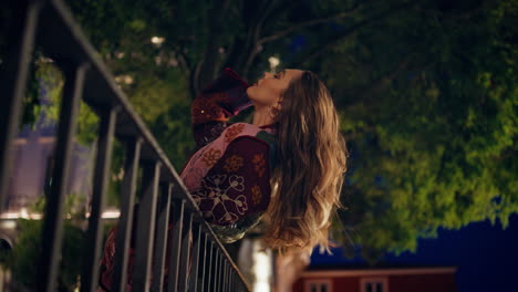 chica elegante de pie al anochecer ciudad apoyándose en las barandillas. mujer en la ciudad de la noche