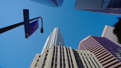 clear blue sky over the tallest skyscrapers in downtown los angeles. american flag flying at financial district building wall.