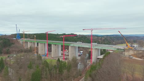 grúas en el puente de la carretera con estructura de hormigón armado durante la construcción