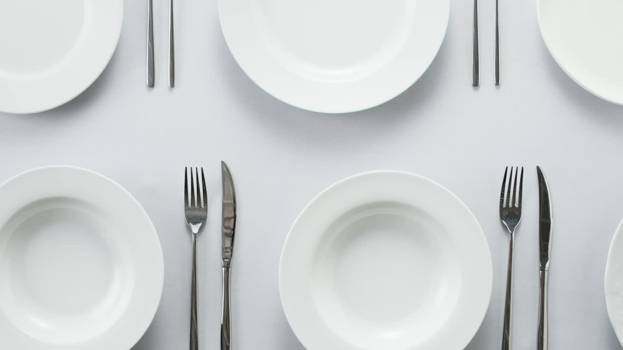 Elegant table setting with white tableware plates, cutlery, and glassware for a classy dining, fancy expensive restaurant dinner