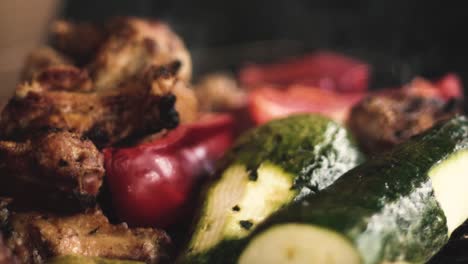 slow-motion close-up chicken wings and grilled vegetables, (italian squash and red pepper or red pepper - smoke from the charcoal grill)