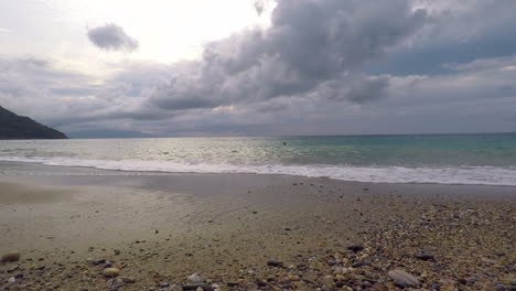 Zeitlupenaufnahme-Von-Meerwasserwellen,-Die-An-Einem-Bewölkten-Tag-Auf-Den-Strand-Treffen