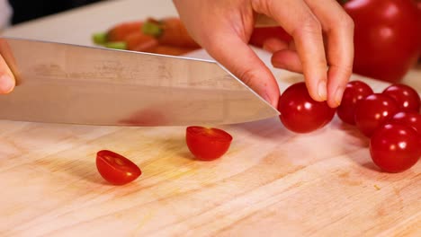 slicing tomatoes with a knife on wooden board