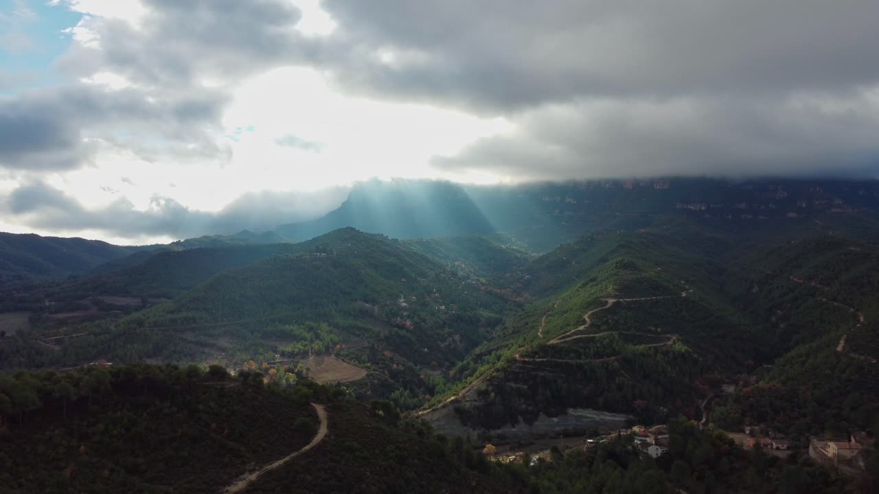los rayos de sol atraviesan las nubes sobre las montañas de montserrat y marganell en barcelona.