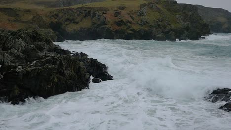 Olas-Rompiendo-En-Las-Rocas-De-La-Costa-En-Cámara-Lenta-En-La-Pantorrilla-Del-Hombre,-Isla-Del-Hombre