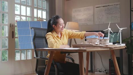 side view of asian woman being happy succeed building a model of small house with solar panel