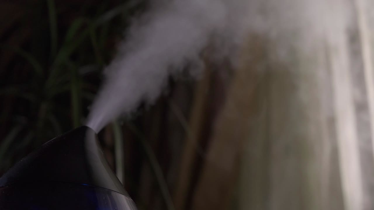 어두운 방에서 현대적인 공기 습기화 장치에서 증기가 나옵니다.