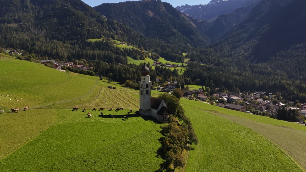 Small church, chiesa in the Italian dolomites. Alpine fields, agricultural grass lands. Aerial video
