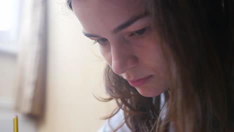 Close-up-shot-of-a-brunette-woman-with-a-pencil-in-her-hand-looking-concentrated-inside-a-room