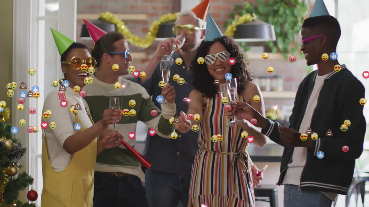 Friends wearing party hats holding champagne and sparklers in kitchen marketing clip showing emojis