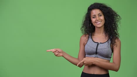 young beautiful hispanic woman with gym clothes showing something