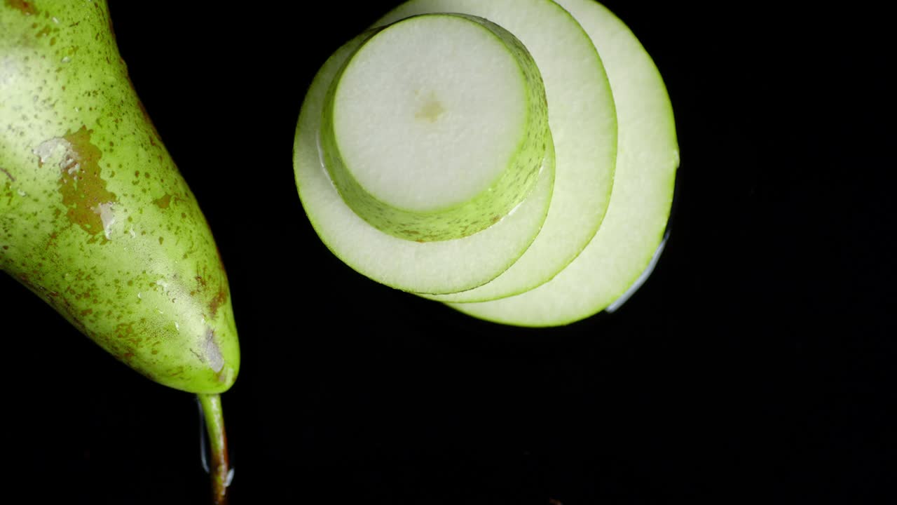 la pera cortada cae al agua con una salpicadura.