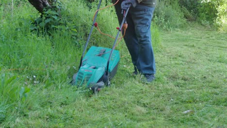 fat obese man gardener mowing the lawn. landscape design. green grass background