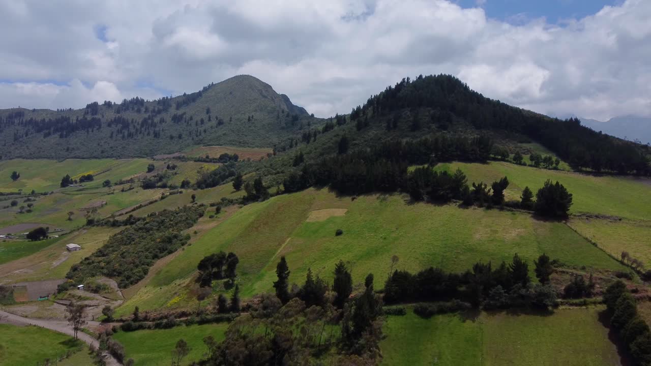 Sorvolo aereo con drone in avanzamento su fattorie e cime montuose boscose