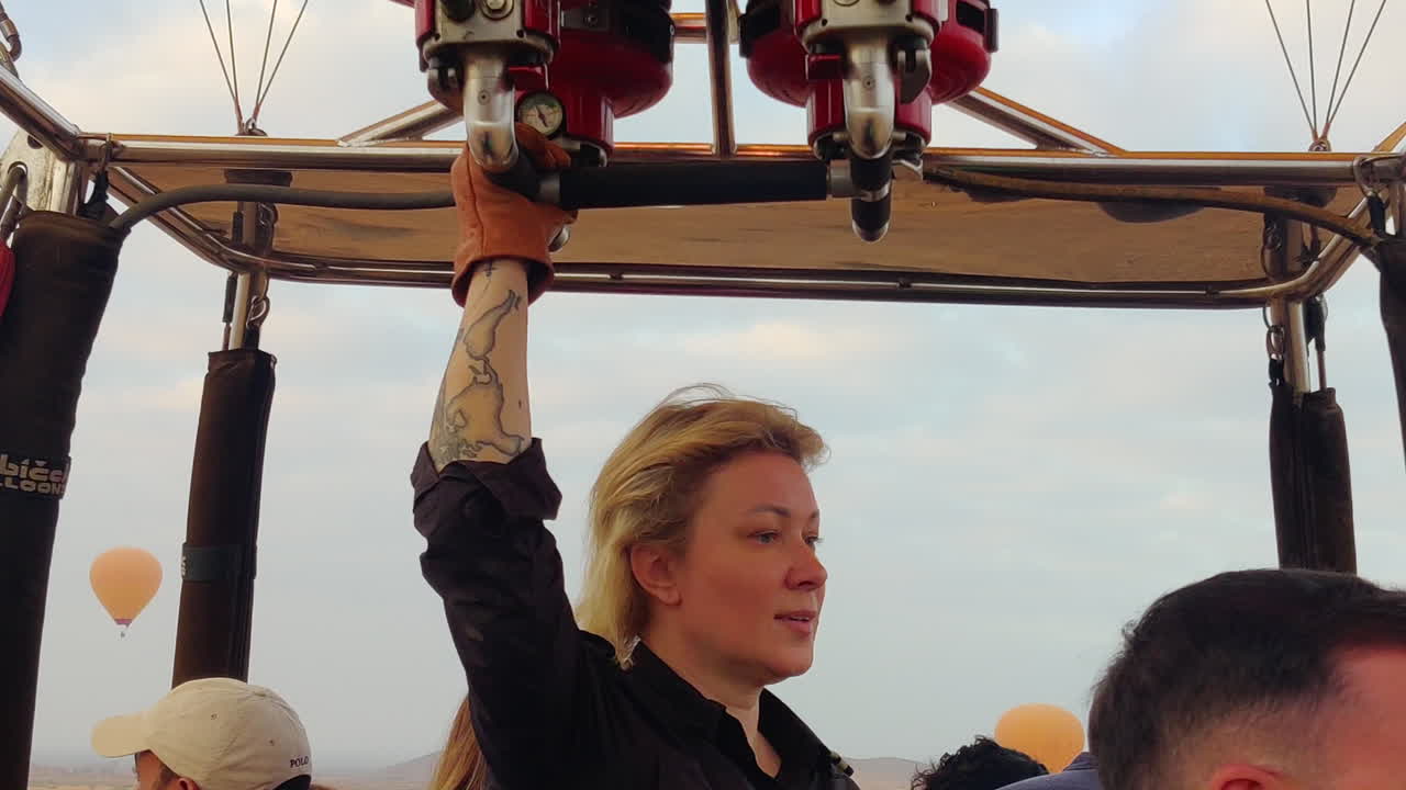 Close up shot on a hot air balloon operator in the air with with tourists in the basket