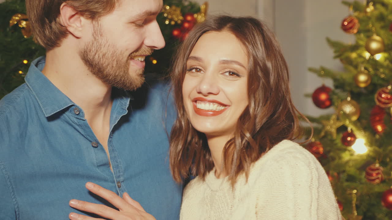 una pareja abrazándose cerca del árbol de navidad.