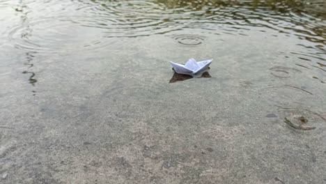 Barco-De-Papel-Sobre-Un-Charco-De-Agua-Durante-La-Lluvia.