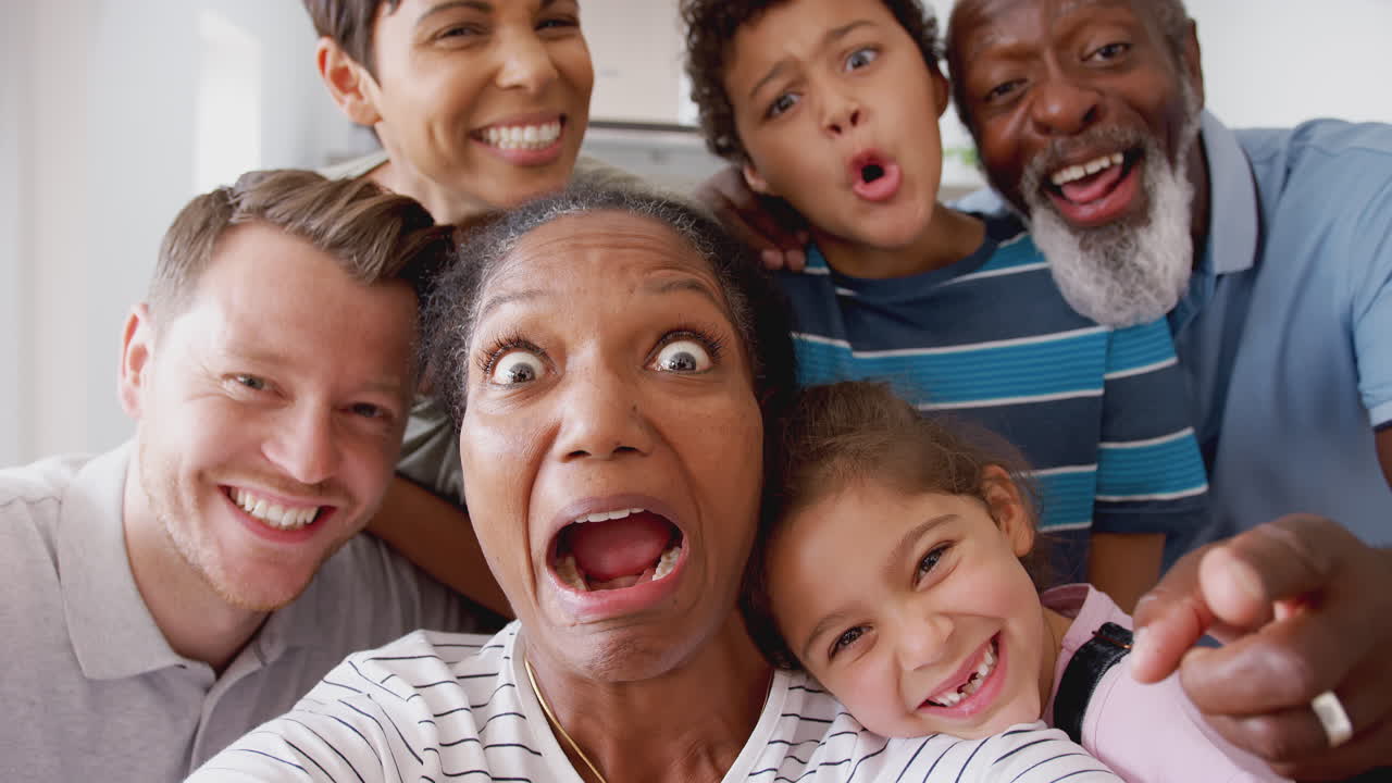 POV Shot Of Multi-Generation Mixed Race Family Posing For Selfie At Home Together