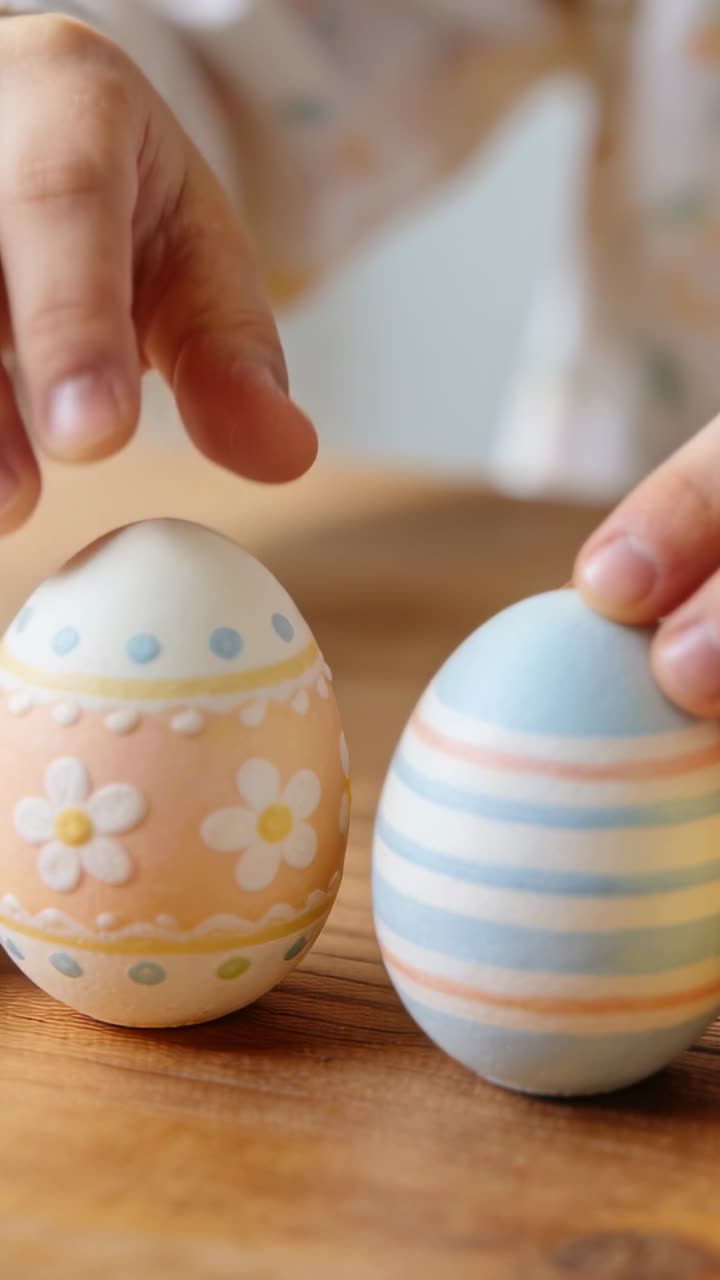 Vertical video: Entering child's hands nudging decorated pastel eggs on wood table for display
