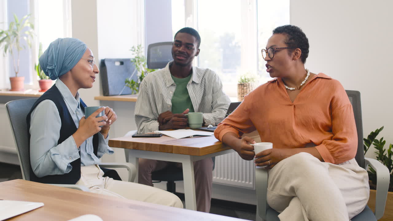 Muslim Businesswoman, Businesswoman And Young Worker Are Talking In The Office While Drinking Coffee 1
