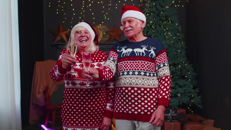 Happy-senior-family-couple-celebrating-Christmas-at-home,-clinking-glasses-and-drinking-champagne