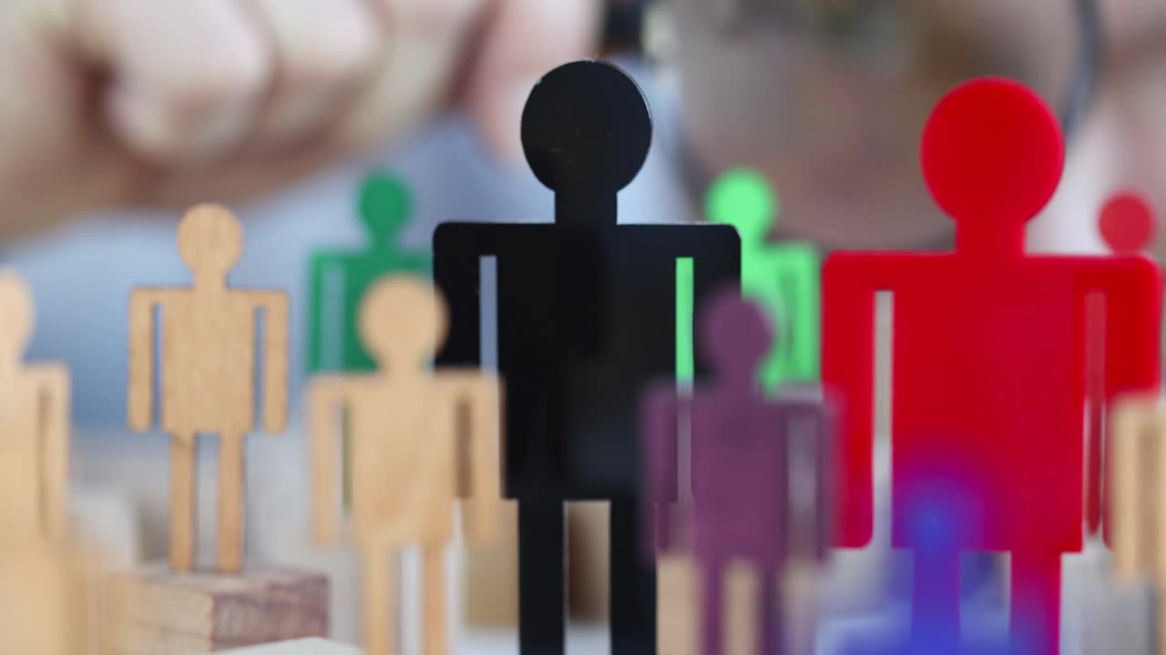 Businessman looking at multicolored toy figures of men through magnifying glass closeup 4k movie