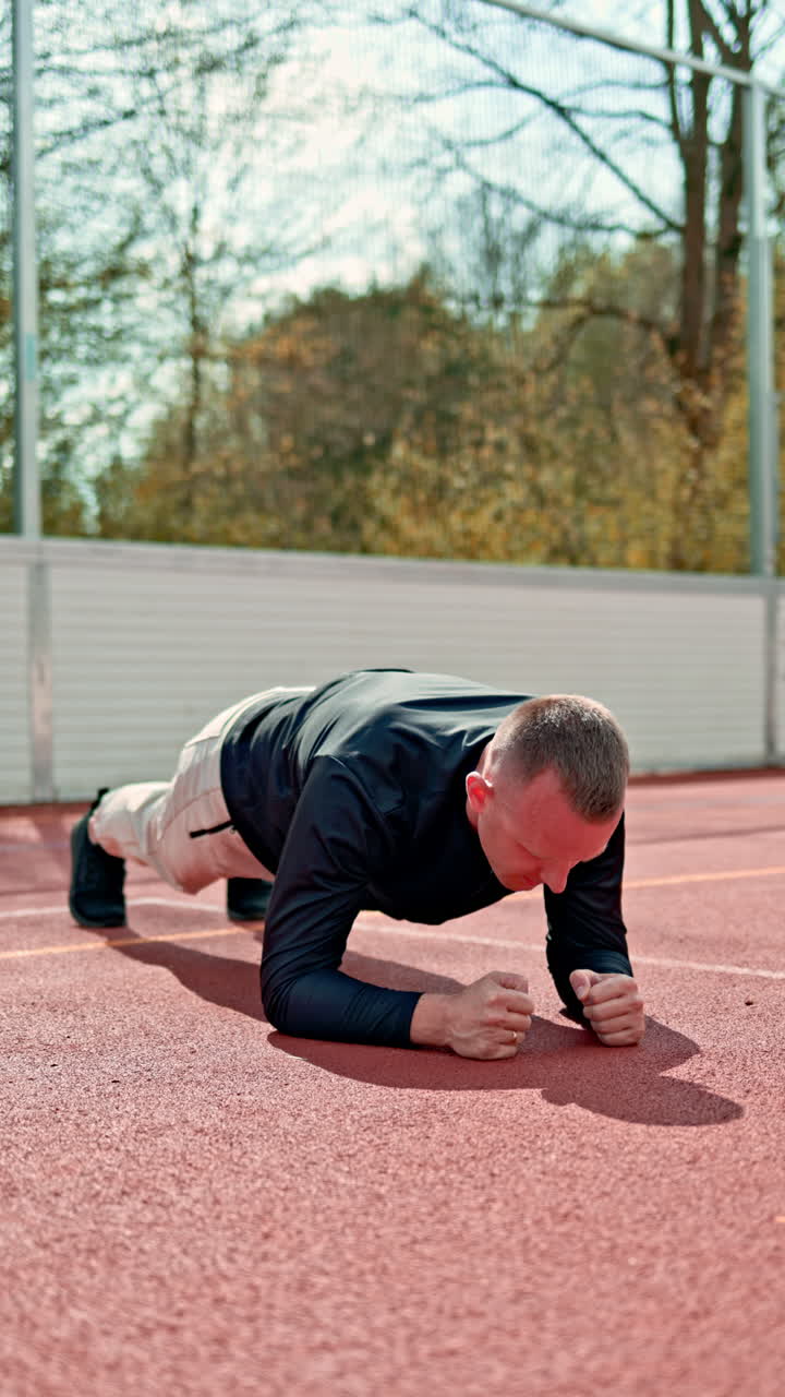 Video di un allenatore sportivo e di un atleta affascinante su un campo sportivo all'aperto. Allenamento all'aperto con uno sfondo cittadino. Allenamento Crossfit.