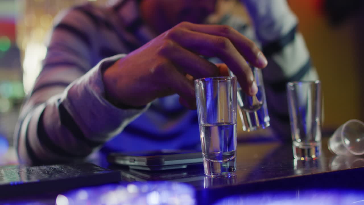 video de la sección media de un hombre afroamericano sentado bebiendo copas en el bar