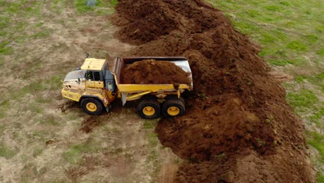 camión volquete amarillo articulado que descarga tierra en el campo, antena