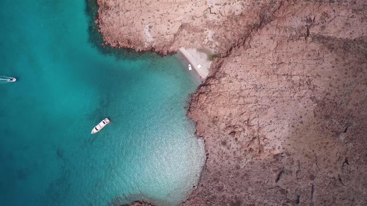 plano aéreo cenital de una pequeña playa y un yate en la isla partida, parque nacional archipiélago espritu santo, baja california sur