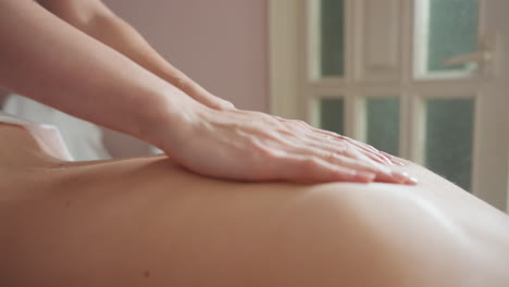 massage therapist gently rubbing cream on client back during soothing body treatment, focusing on smooth motion and wellness care in calm indoor environment with soft lighting and natural tones