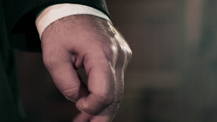 Uomo caucasico in abito che stringe i pugni, primo piano ravvicinato sulle mani