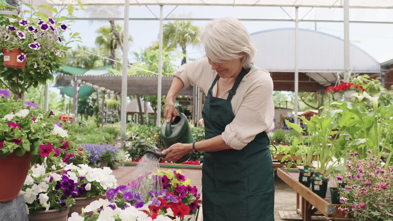 Donna anziana che coltiva fiori in una serra