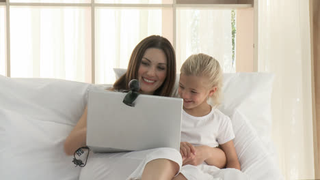 hermosa madre e hija teniendo una conferencia telefónica en la cama