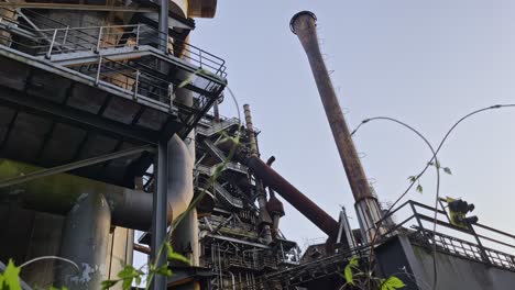 historic green industrial building surrounded by nature with steel stairs and pipes and schronsteienen landschaftspark, duisburg, germany