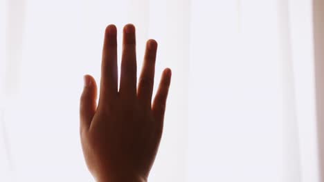 female hand silhouette over curtain flashing sunlight