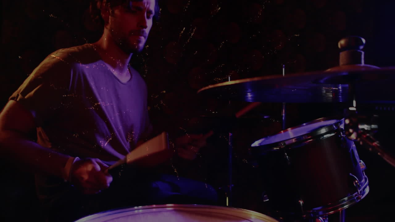 Male drummer playing drums under purple blue lights, showing golden sparks in music industry