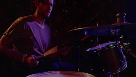 male drummer playing drums under purple blue lights, showing golden sparks in music industry