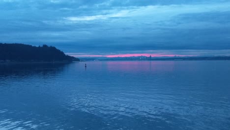 On-the-bow-of-the-Bremerton-Seattle-Ferry-during-the-blue-sunrise-hour,-calm-water,-golden-glow-in-the-clouds