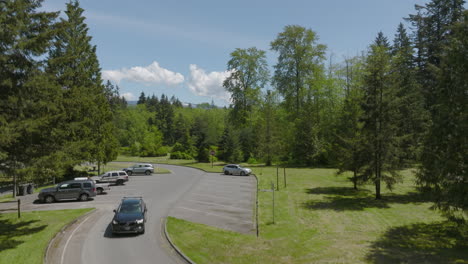 El-Automóvil-Sale-Del-Estacionamiento-De-La-Parada-De-Descanso-Y-Se-Dirige-Hacia-La-Cámara-Con-La-Pluma-Levantada-Para-Revelar-El-Paisaje-Y-El-Horizonte-De-Bellingham,-Washington-En-Un-Día-Magnífico