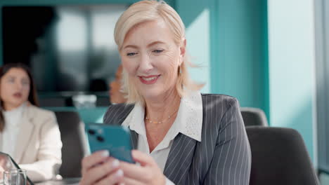 senior businesswoman laughing at a mobile phone in a conference room