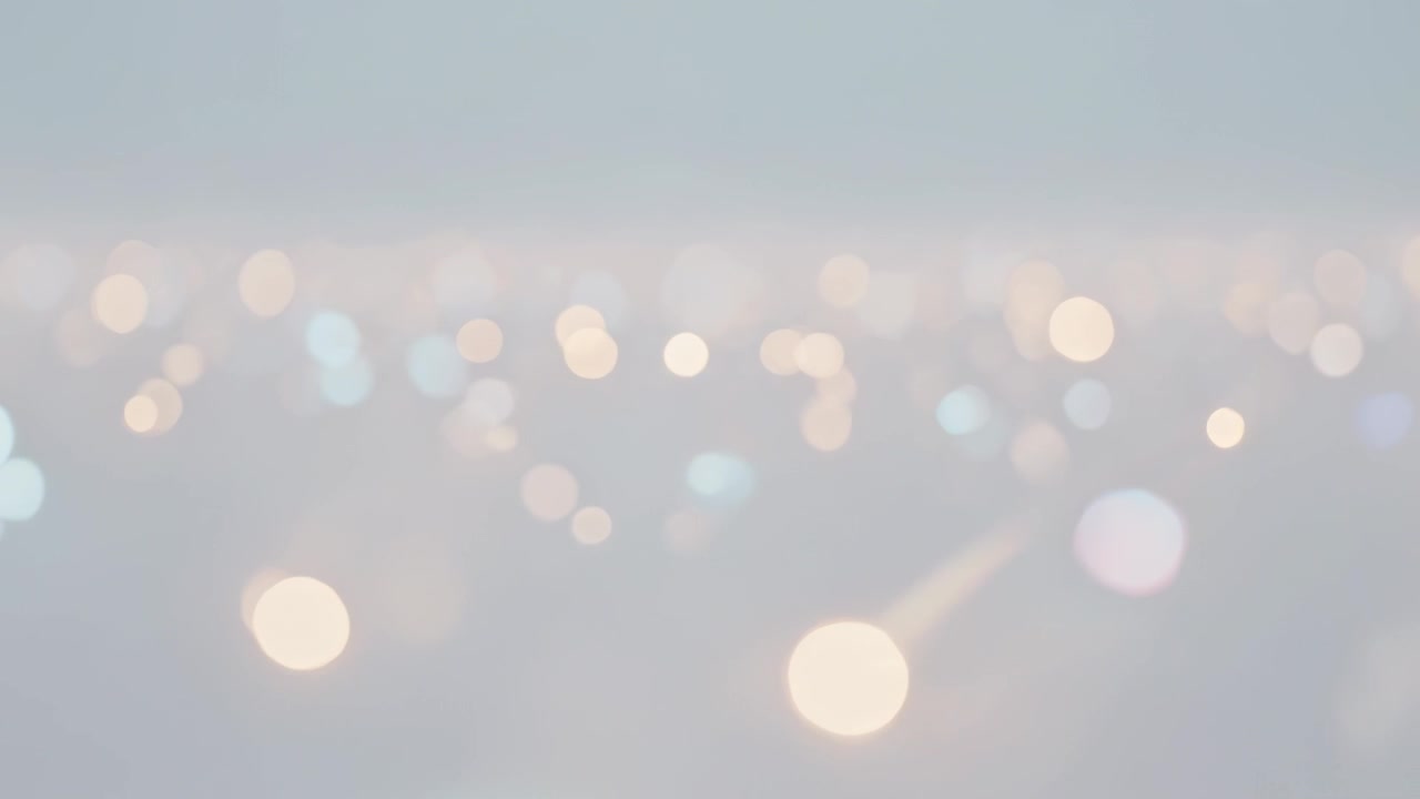 Shifting blurred point lights drifting across pale sky band at twilight, during focus shift