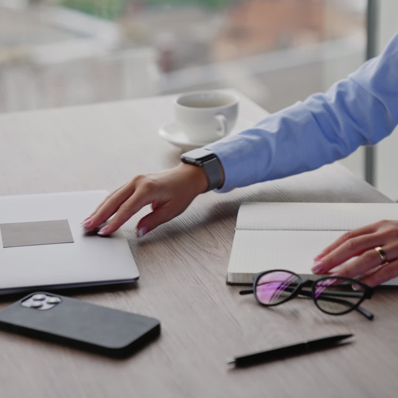 Unrecognizable woman sitting at desk. Female hands close laptop and paper notebook. Office employee finishes working day