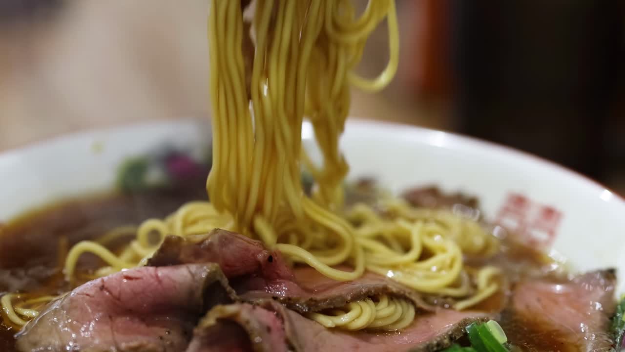 한 사람이 그에서 가락으로 라멘을 먹고 있다