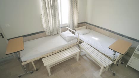two empty hospital beds with side tables and benches in a karachi hospital room, ready for incoming patients