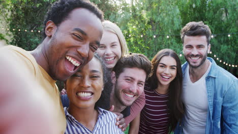 group of multi-cultural friends posing for selfie as they enjoy outdoor summer garden party