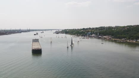 river scene with cargo ship and sailboats