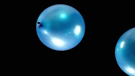 watch blue shining balloons fall gracefully in slow motion, their shimmering surface catching the light as they gently descend. the peaceful movement creates a mesmerizing and tranquil visual.